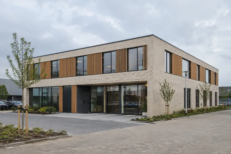 Nieuw kantoorgebouw met lichte baksteen, houten zonwering en grote ramen