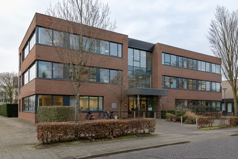 Bestaand Nederlands kantoorgebouw met vernieuwde ramen en fietsen bij de entree