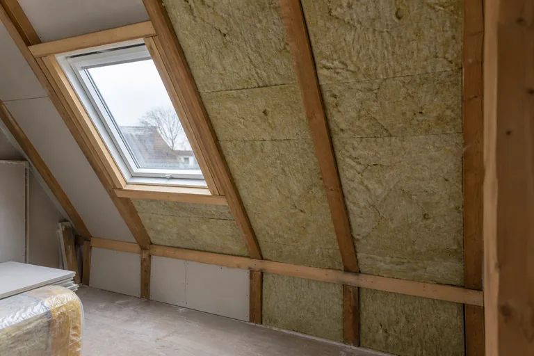 Isolatiemateriaal tussen houten dakbalken tijdens een zolderrenovatie